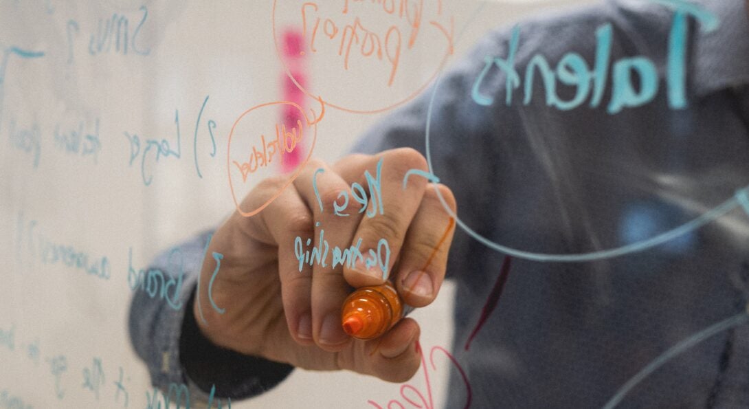 person writing on a transparent glass called a lightboard