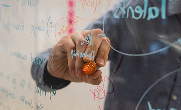 an instructor writes on a transparent surface while teaching